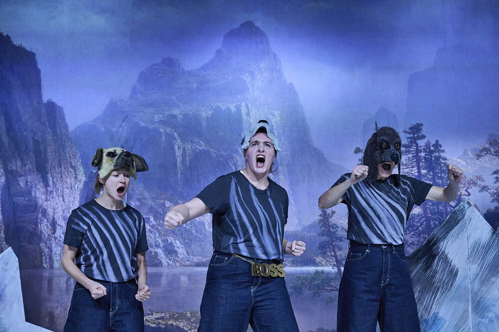Drei schreiende Schauspielerinnen mit Hundemasken vor einer Berglandschaft