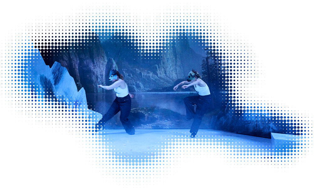 Zwei Schauspielerinnen mit Hundemasken vor einer mit Schnee bedeckten Berglandschaft in Alaska.